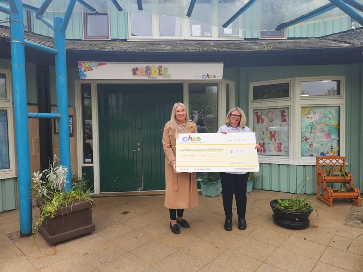 Premier Properties Perth presents a donation cheque to CHAS outside a CHAS service building